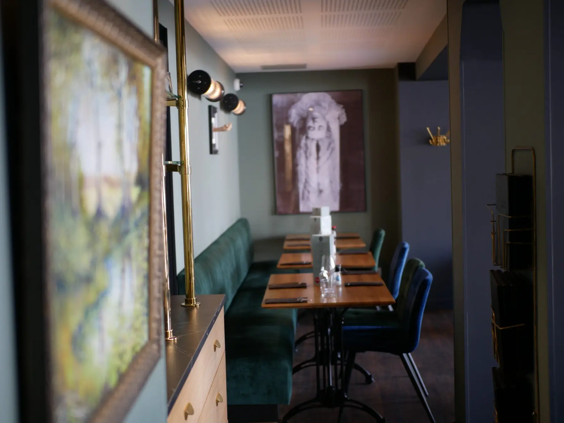 Salle du Café Gourmand : banquettes de velours vert et tables dressées.