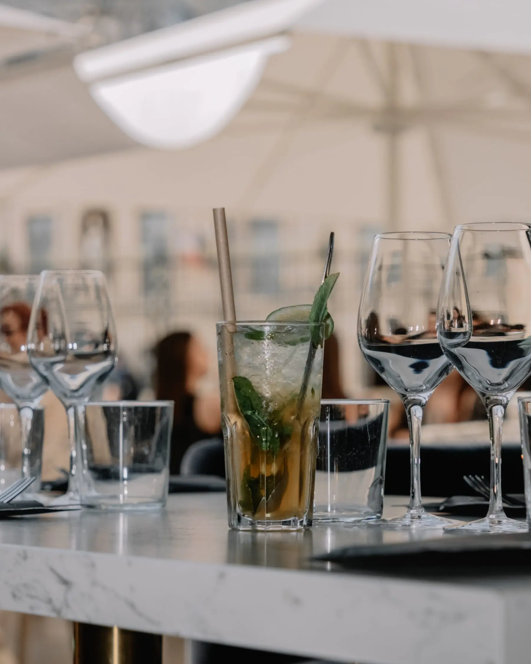 Wine glasses and a mojito on a marble table on the terrace beneath the parasols.